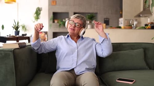 Senior Woman Dancing to Music on Couch