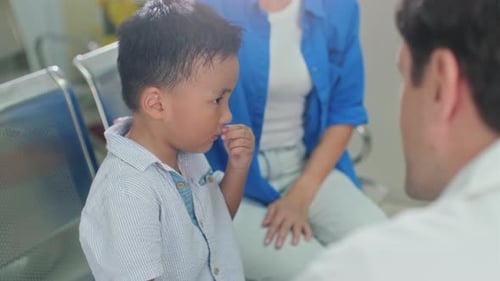Pediatrician Talking to Asian Boy about Symptoms of His Illness