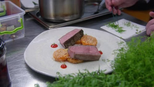 Chef Garnishing Slices of Steak in Restaurant Kitchen