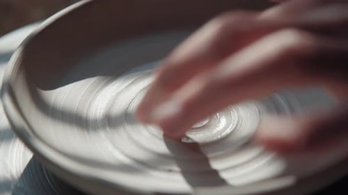 Potter Makes Plate From White Clay Draws a Spiral By Finger Close Up