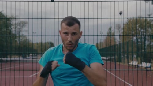 Man Boxing, Practicing Punches Outdoors on Overcast Day