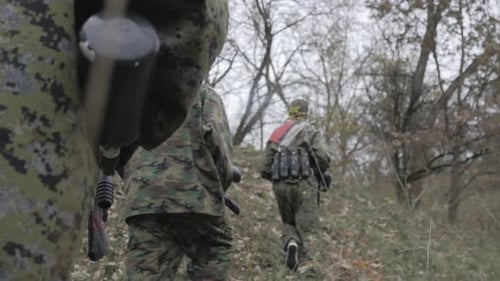 Paintballspieler gehen in Zeitlupe durch den Wald