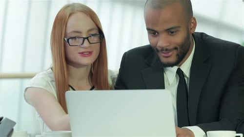 Four Smiling Successful Businessmen Sitting at Table in Office While Discussing