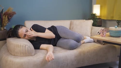 La jeune femme allongée sur le canapé pleure.