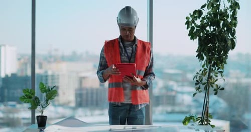 Construction Worker Carefully Analyzing Detailed Plans in a Modern Office Environment