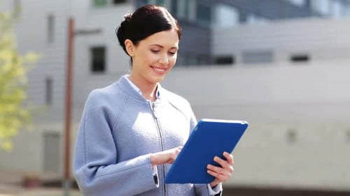 Young smiling businesswoman with tablet pc computer overlooking the city office