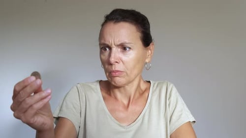 Woman Looks Questioningly at Coin in Studio