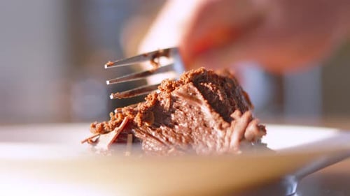 Close Up of Fork Cutting Piece of Milk Cake Dessert in Sunlight with Shallow DOF Bokeh.