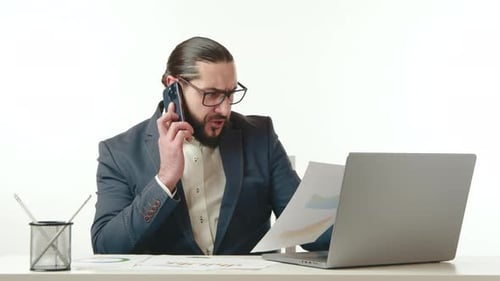 Man Talking on Phone at Desk with Laptop