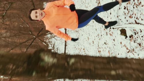 Young confident woman wearing sports clothing jogging in forest. Vertical video