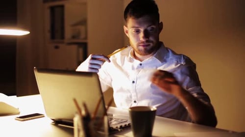 Man Working Late at Computer with Lamp Light
