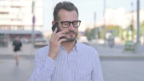 Man in City Uses Mobile Phone and Talks