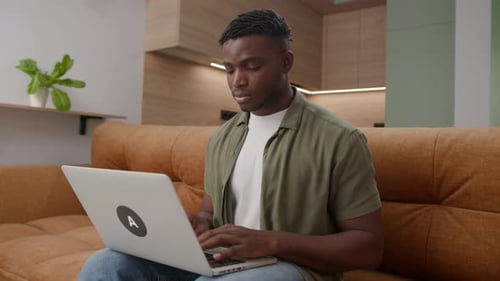 A Focused Man Works on His Laptop at Home
