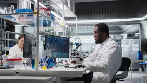 Scientists Working with Microscopes and Computers in Lab