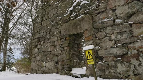 Danger falling rocks sign in church ruin in winter day. Tilt down