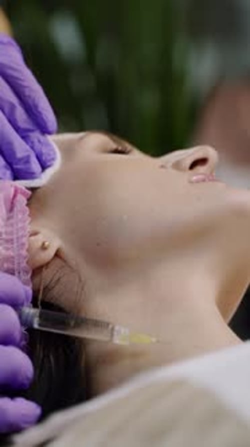 Beauty clinic. Beautician hands in gloves making face anti-aging injection in a female neck.