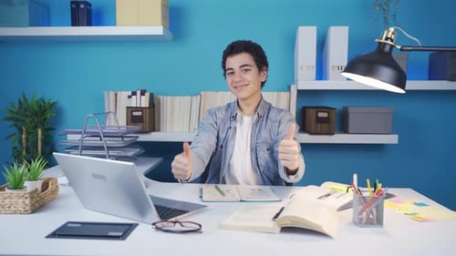 Young Man Studying and Smiling at Desk