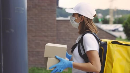 Vue latérale de la coursière caucasienne se rendant chez le client avec les boîtes en papier qui portaient