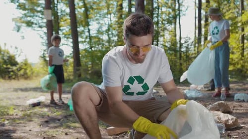 Man in Yellow Gloves Picks Litter in a Tranquil Forest Urging Conservation