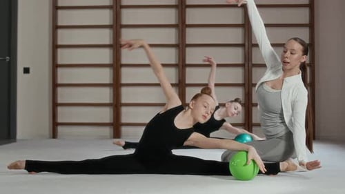 Gymnastics Coach and Girls Stretching Indoors