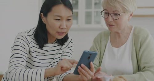 Adult and Senior Looking at Cell Phone Together