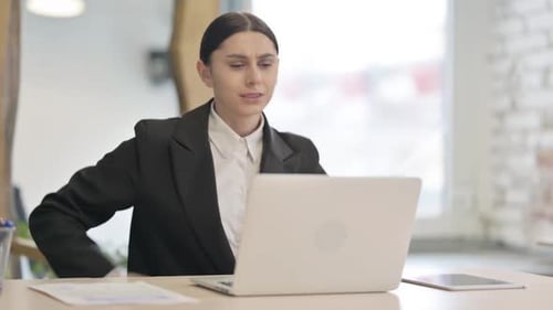 Woman Working at Laptop in Office Experiencing Back Pain