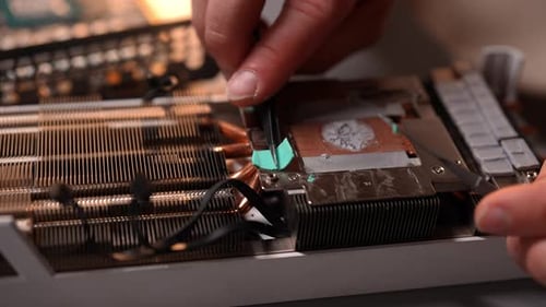 Computer Repair Technician Removing Old Thermal Paste From Graphics Card Using Metal Spatula in