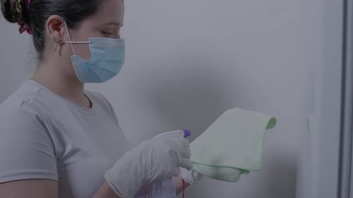 Woman in Mask Cleans with Spray and Cloth