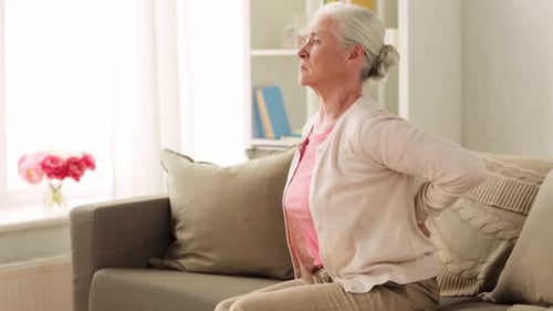 Senior Woman Massaging Back While Sitting on Couch
