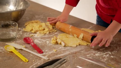 hands of child dressed in red kneading flour and preparing to bake cookies or homemade bread
