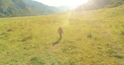 Flight Over Backpack Hiking Tourist Walking Across Green Mountain Field Huge Rural Valley at Summer