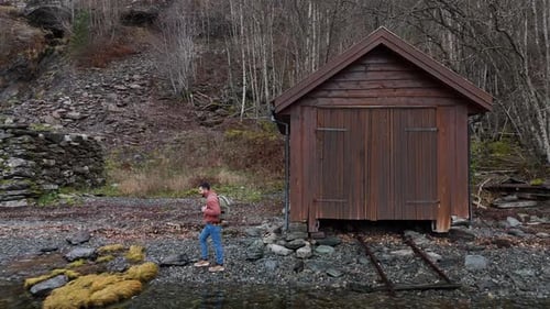 young backpacker man walking through a fjord in norway on a cloudy day at sunset