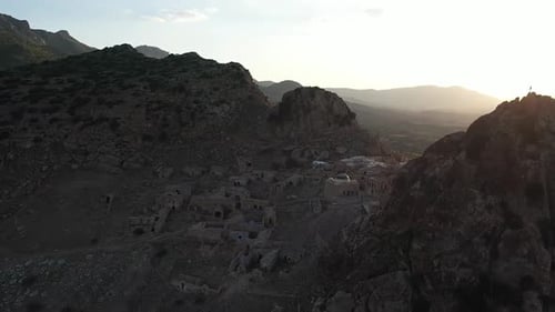 Aerial shot moving to the right and back over the small ancient village in ruins, next to a steep ro