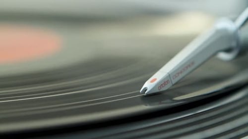 A close-up shot of a turntable needle playing a vinyl record in soft focus, capturing nostalgia