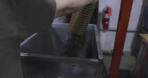Man Filling Container with Material via Corrugated Tube