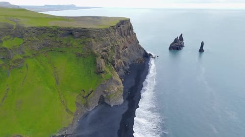 Aerial Shot of Icelandic Landscapes with Rocks on Blacksanded Beach at Sea