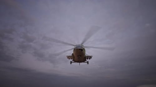 Front View of Military Helicopter Hovering Against Cloudy Sky