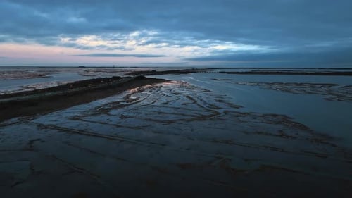 An aerial view over the salt marsh in Freeport, NY during a cloudy sunset. The camera dolly in over