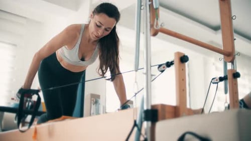 Woman Exercising on Pilates Reformer Machine