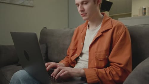 Young Adult Typing on Laptop While Sitting on Couch