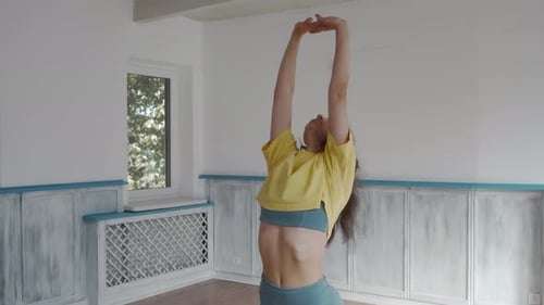 A woman practices flexibility exercises on a yoga mat in a workout studio.