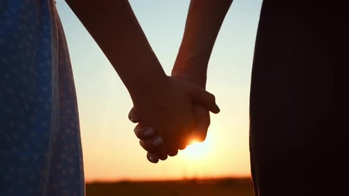 Closeup Romantic View of Couple Holding Hands Against Blurred Sky and Sunset