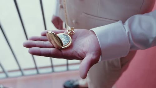 Man Holds Gold Pocket Watch in His Hand