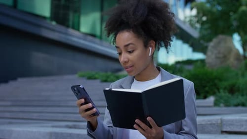 Woman Works on Phone with Notebook Outside