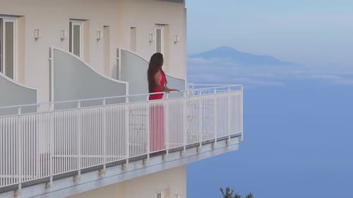 Woman in Red Dress on Balcony Overlooking Amalfi Coastline in Italy