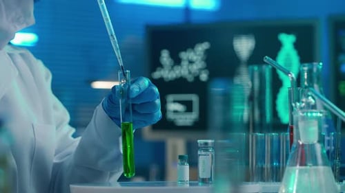 A Female Scientist Pipettes a Red Drop Into a Test Tube with a Green Liquid and Examines the Sample