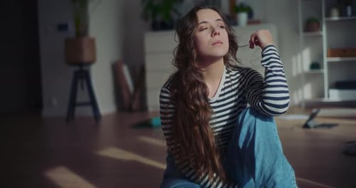 Woman Sitting on Floor in Sunlight Thinking