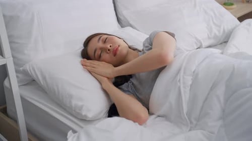 Woman Sleeps Soundly in Bed in Bright Bedroom