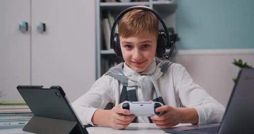 Kleiner Junge spielt Videospiel auf Gamepad und sitzt im Wohnzimmer. Kinder träumen davon, zu Hause zu bleiben, lustiger Computer