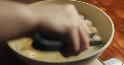 Femme cuisinant des pétoncles à la maison dans sa cuisine faisant frire des pétoncles de mer dans une poêle sur une cuisinière à gaz portable
